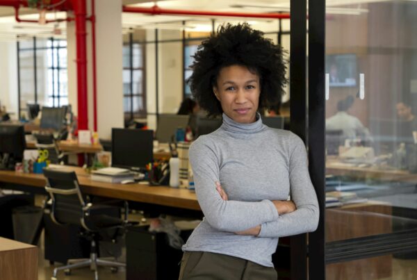 Person standing confidently in a modern office setting.